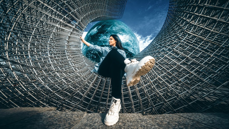 Young professional standing inside a wire sculpture in front of a glass sphere, looking ahead