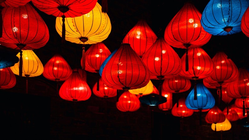 Red, yellow and blue silk lanterns glowing at night, representing regional markets