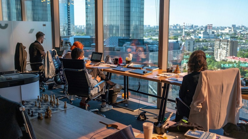 Professionals working at desks in an office overlooking the city