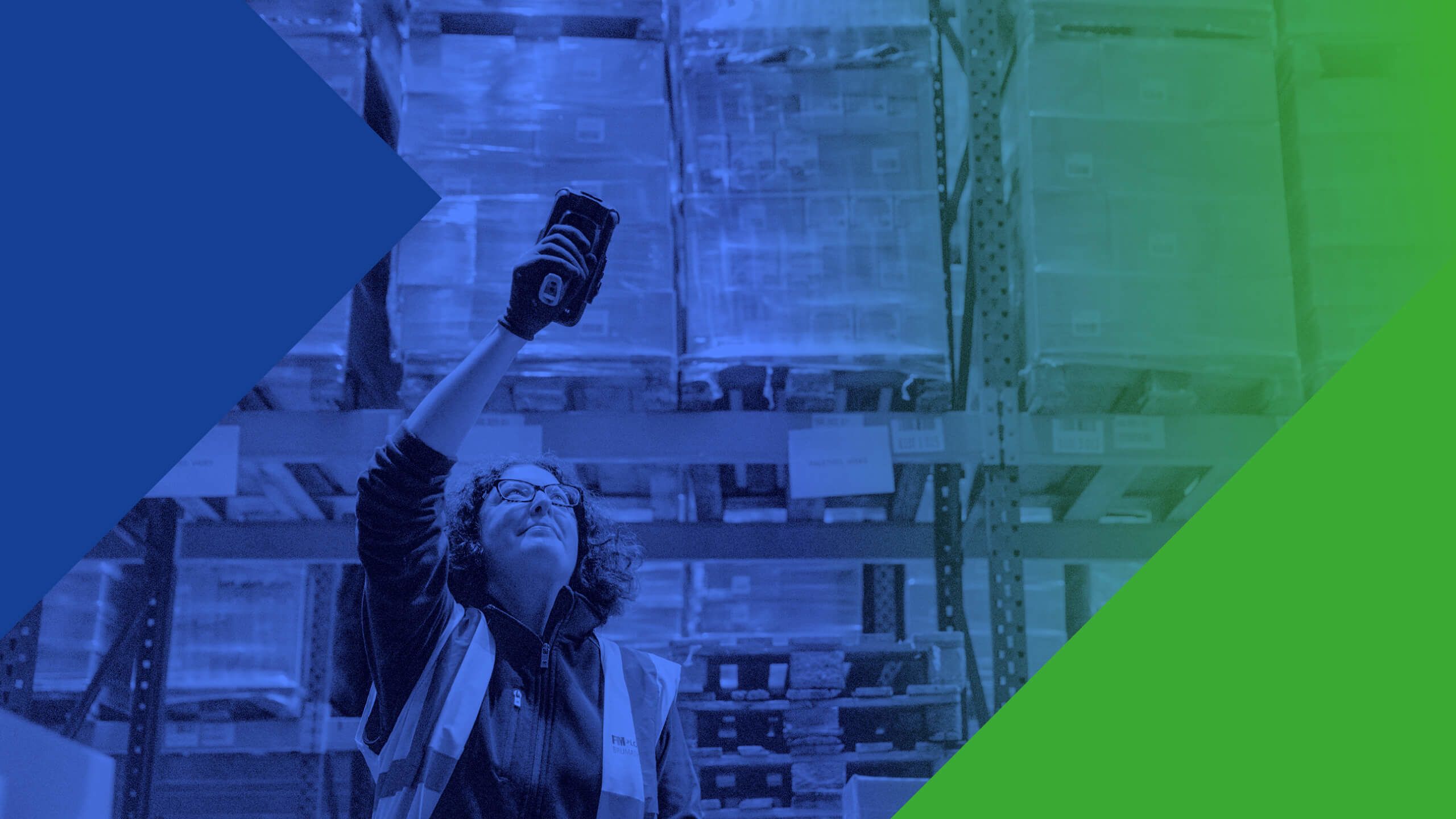 Woman wearing a high-vis jacket in a warehouse using a barcode scanner