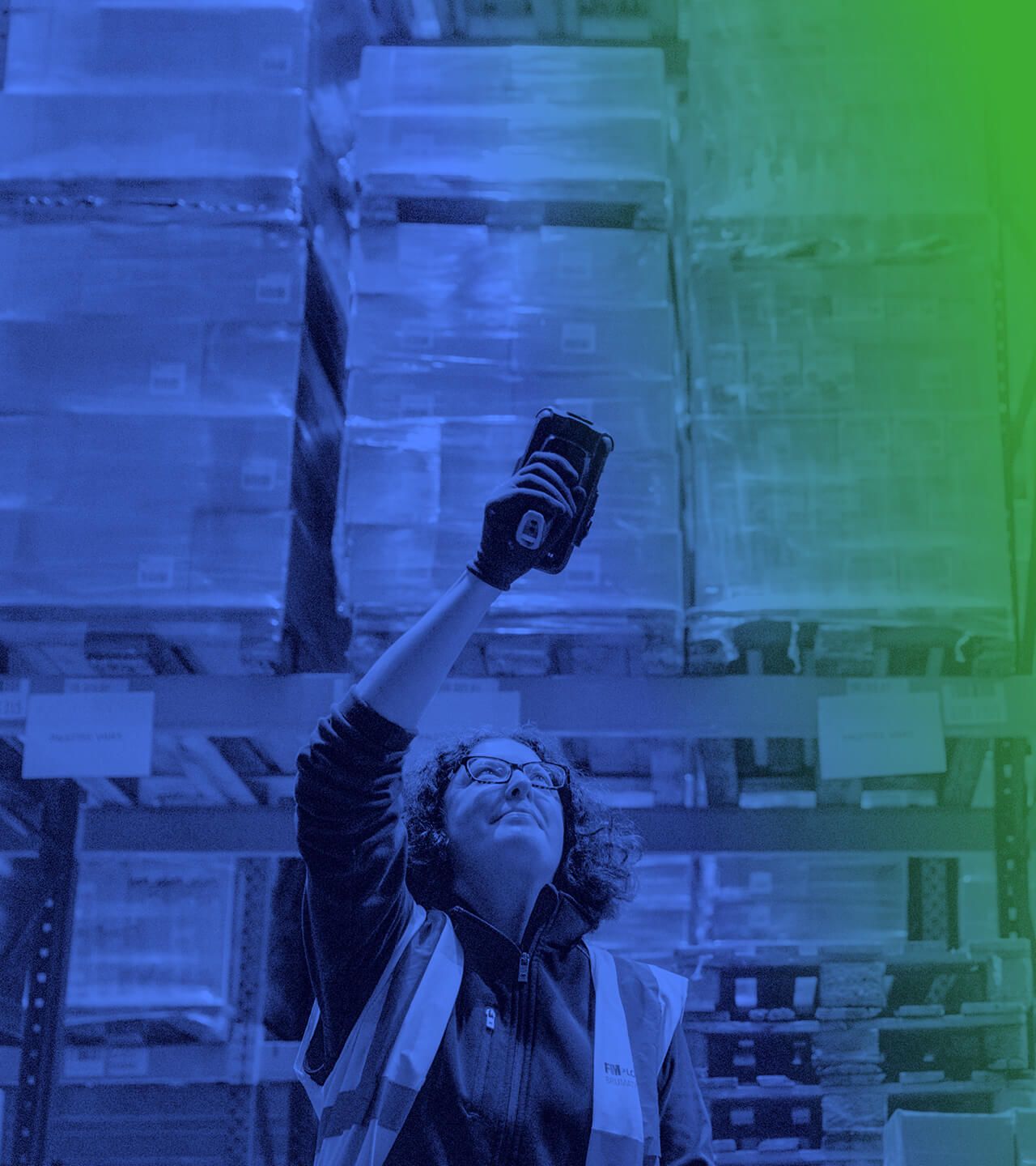 Woman wearing a high-vis jacket in a warehouse using a barcode scanner